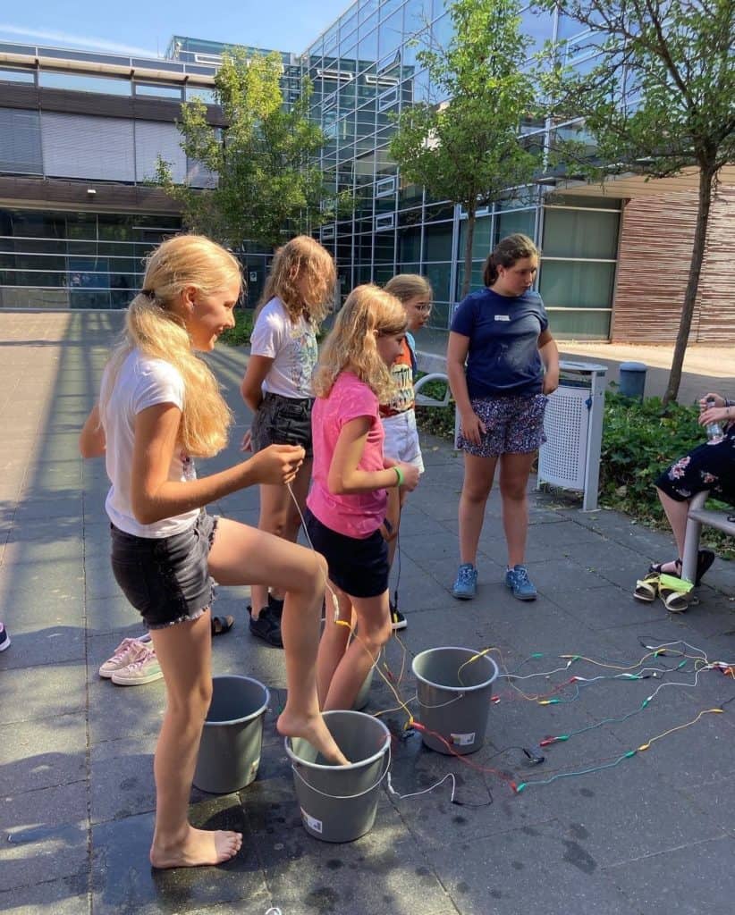 Schülerinnen steuern programmiertes Spiel mit ihren Füßen und Wasser